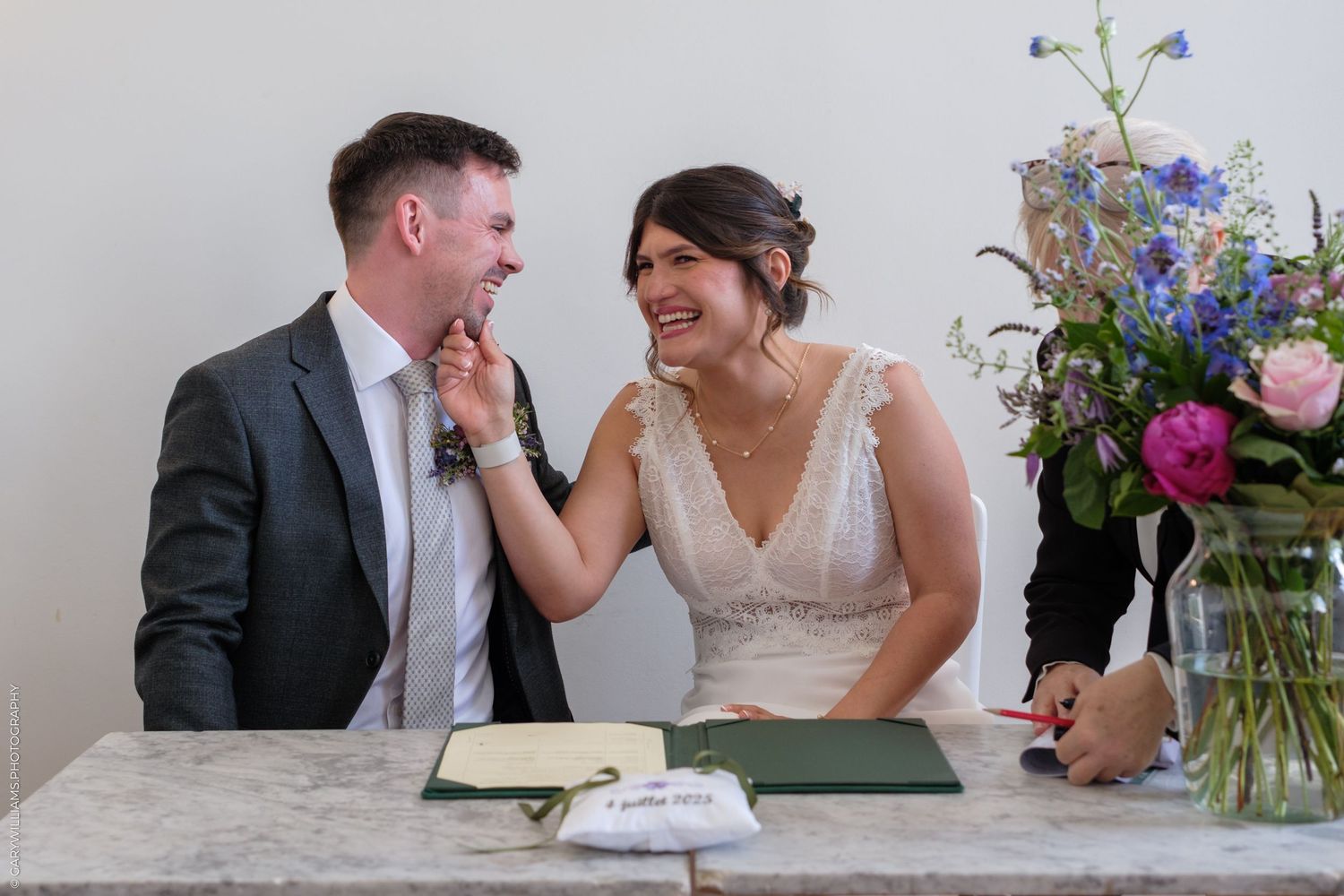 Tender moment shared between a couple with colorful wildflowers in a vase on a light table.