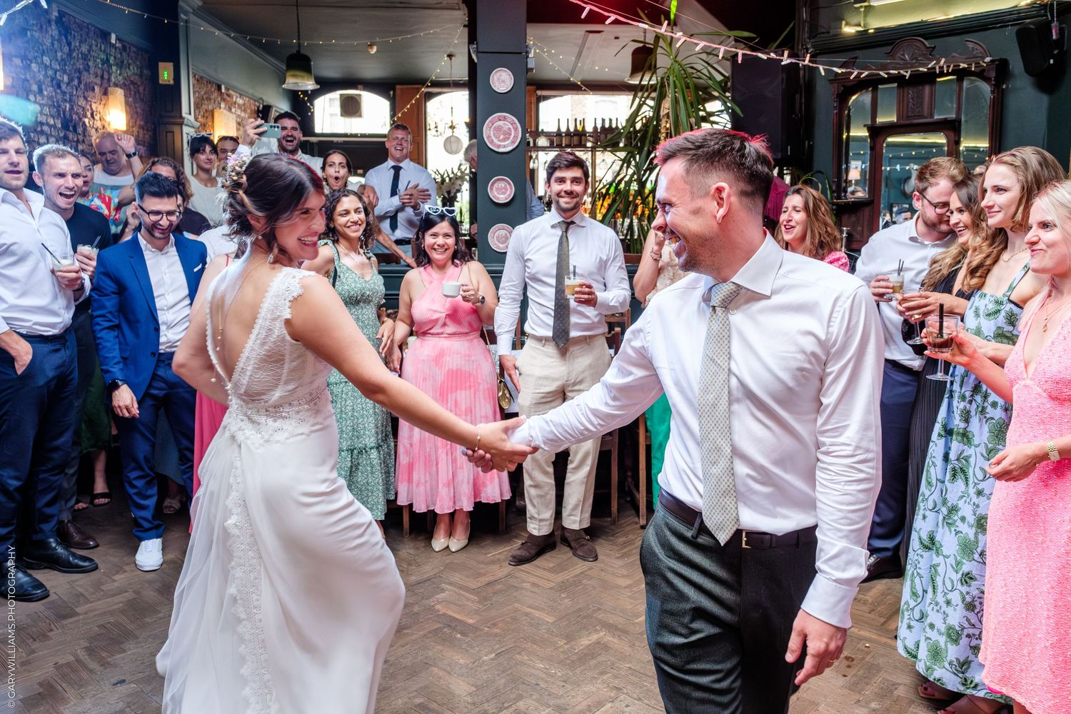 Wedding guests watch as a couple dances together during their reception celebration at an indoor venue.