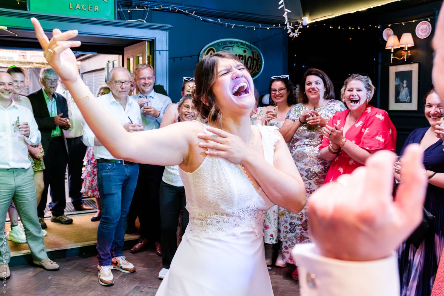 Group celebrating and dancing together at a wedding reception with expressions of joy and laughter.