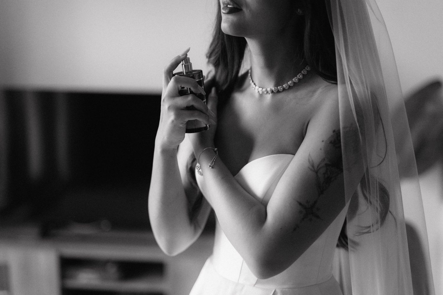 Black and white wedding photography shows bride preparing for ceremony with lipstick application.