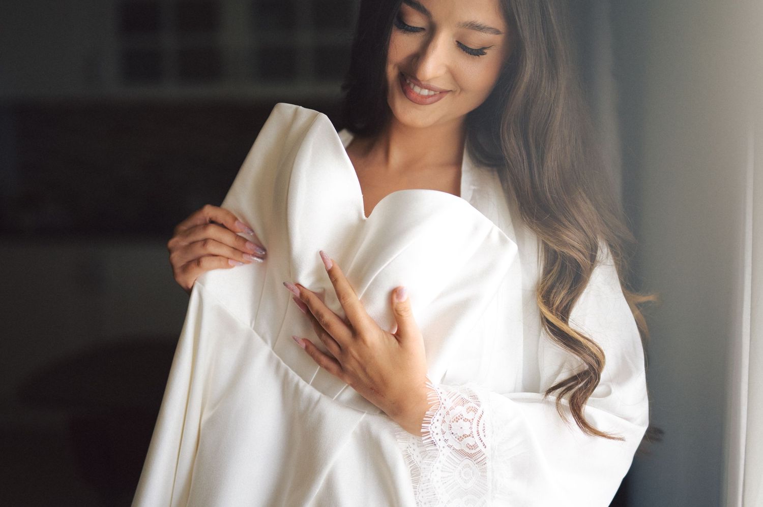Elegant portrait of person in white clothing glancing downward with long dark hair.