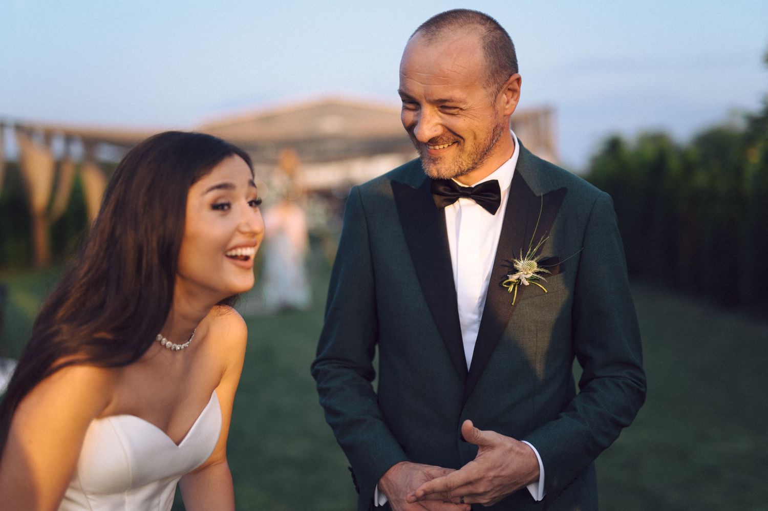Happy newlyweds share a joyful candid moment together during outdoor wedding reception.