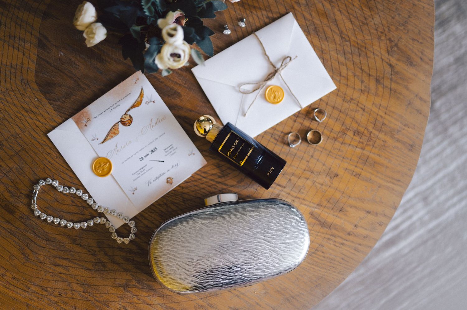 Wedding invitation cards and accessories displayed on a rustic wooden table with envelopes and a decorative case.