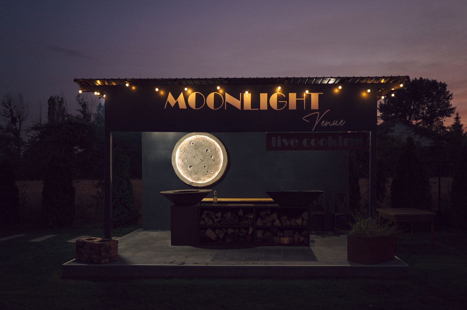 An illuminated 'Moonlight' sign with a glowing circular light display at an outdoor evening venue.