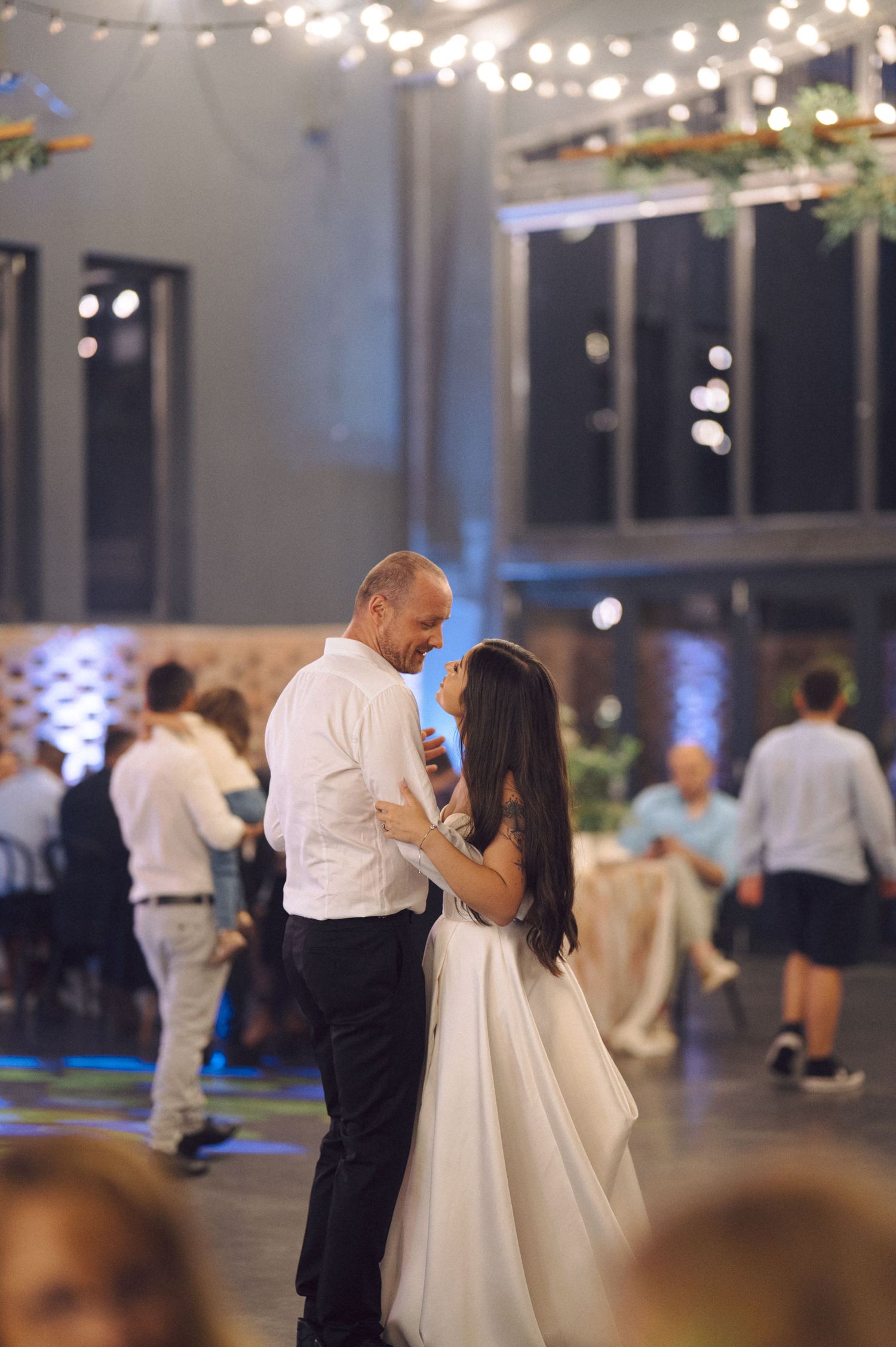 Couple sharing an intimate dance at a wedding reception under string lights.