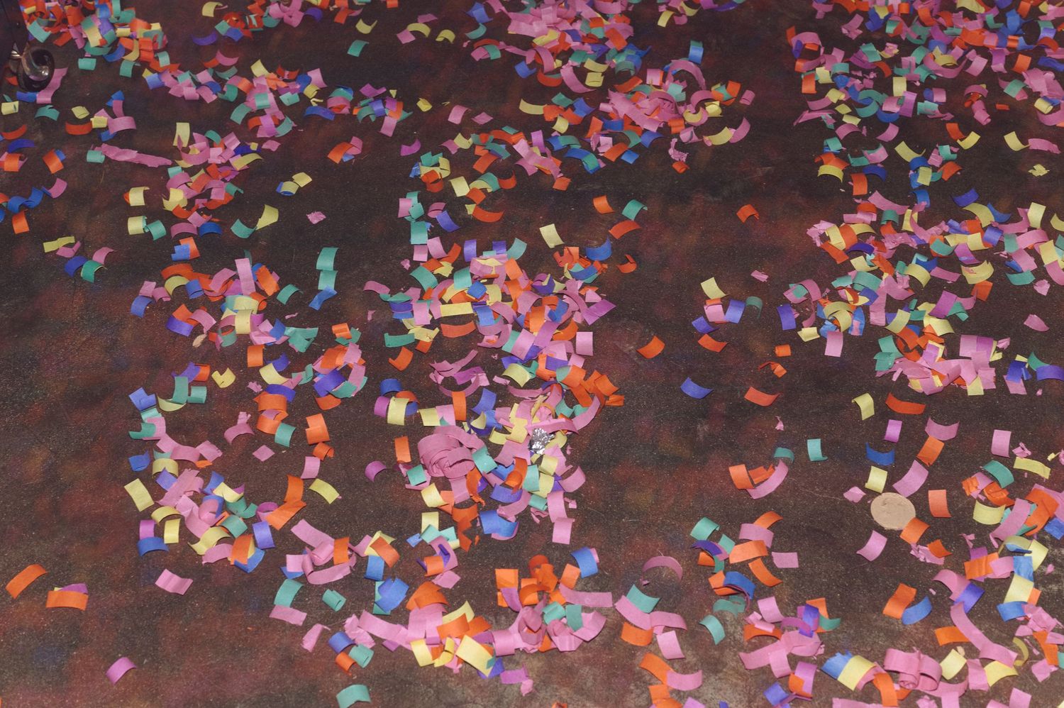 Colorful confetti scattered across a dark floor creates a festive party atmosphere.