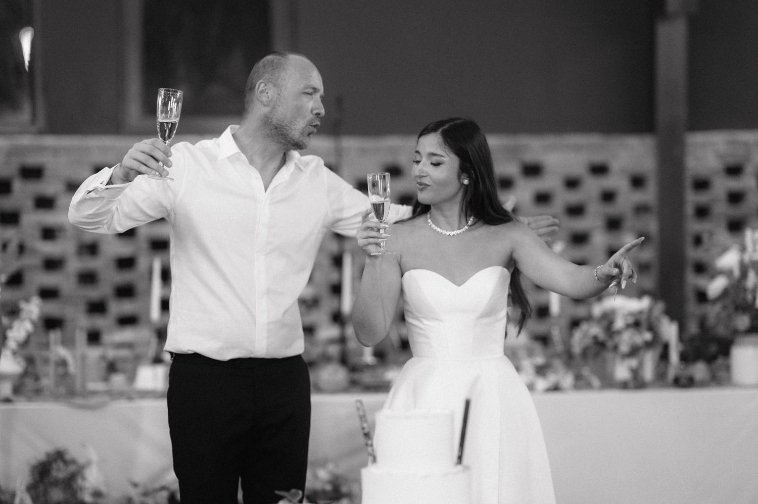 A couple dancing and celebrating with champagne glasses at an elegant wedding reception.