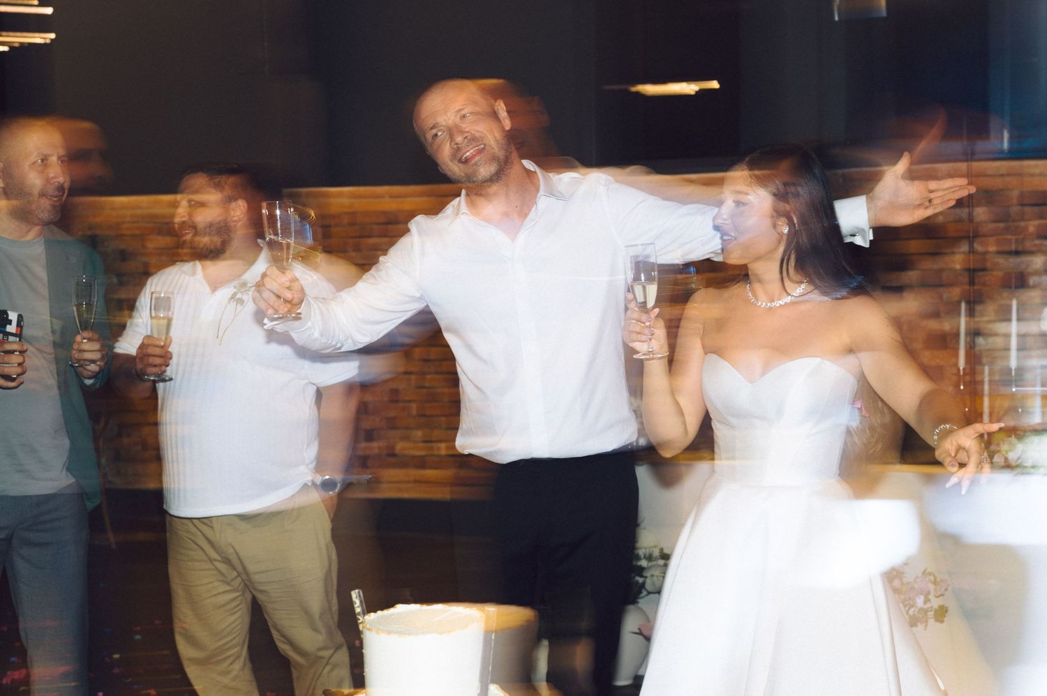 Wedding party dancing and celebrating on a rustic indoor dance floor.