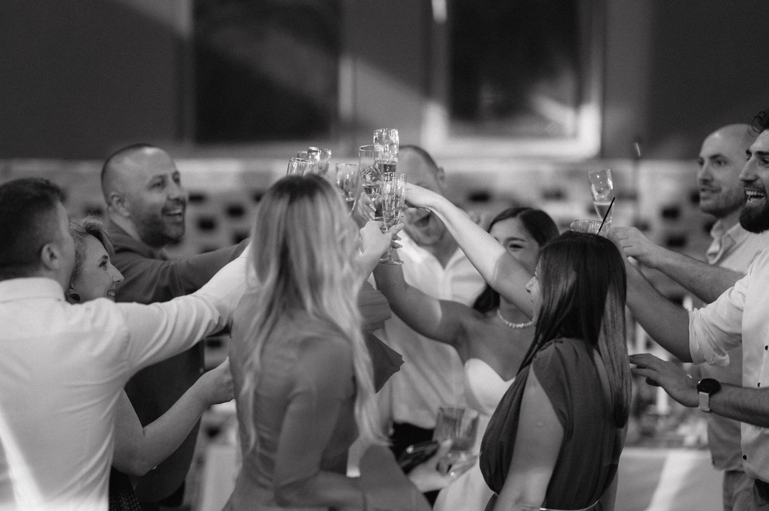 Group of people toasting with drinks at celebration in black and white.