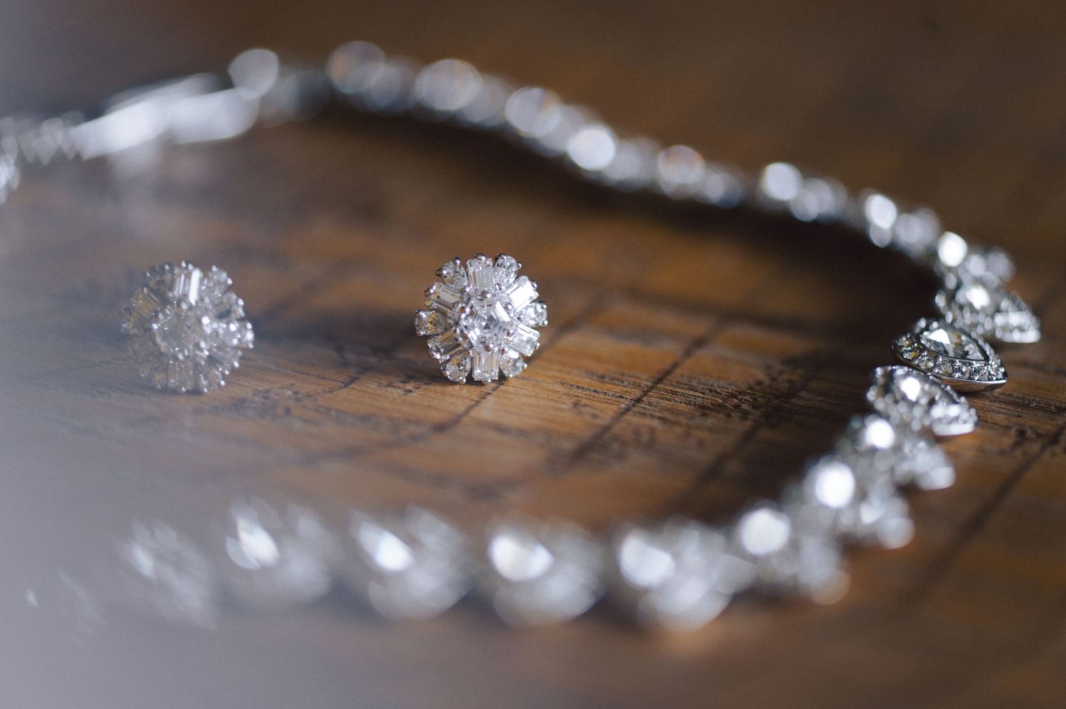 Delicate beaded crystal bridal tiara lying on rustic wooden surface with shallow depth of field.