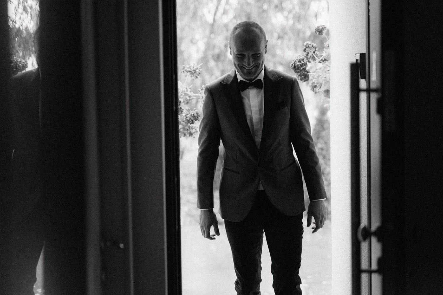 Person in formal attire walks down a dark hallway in dramatic silhouette lighting.