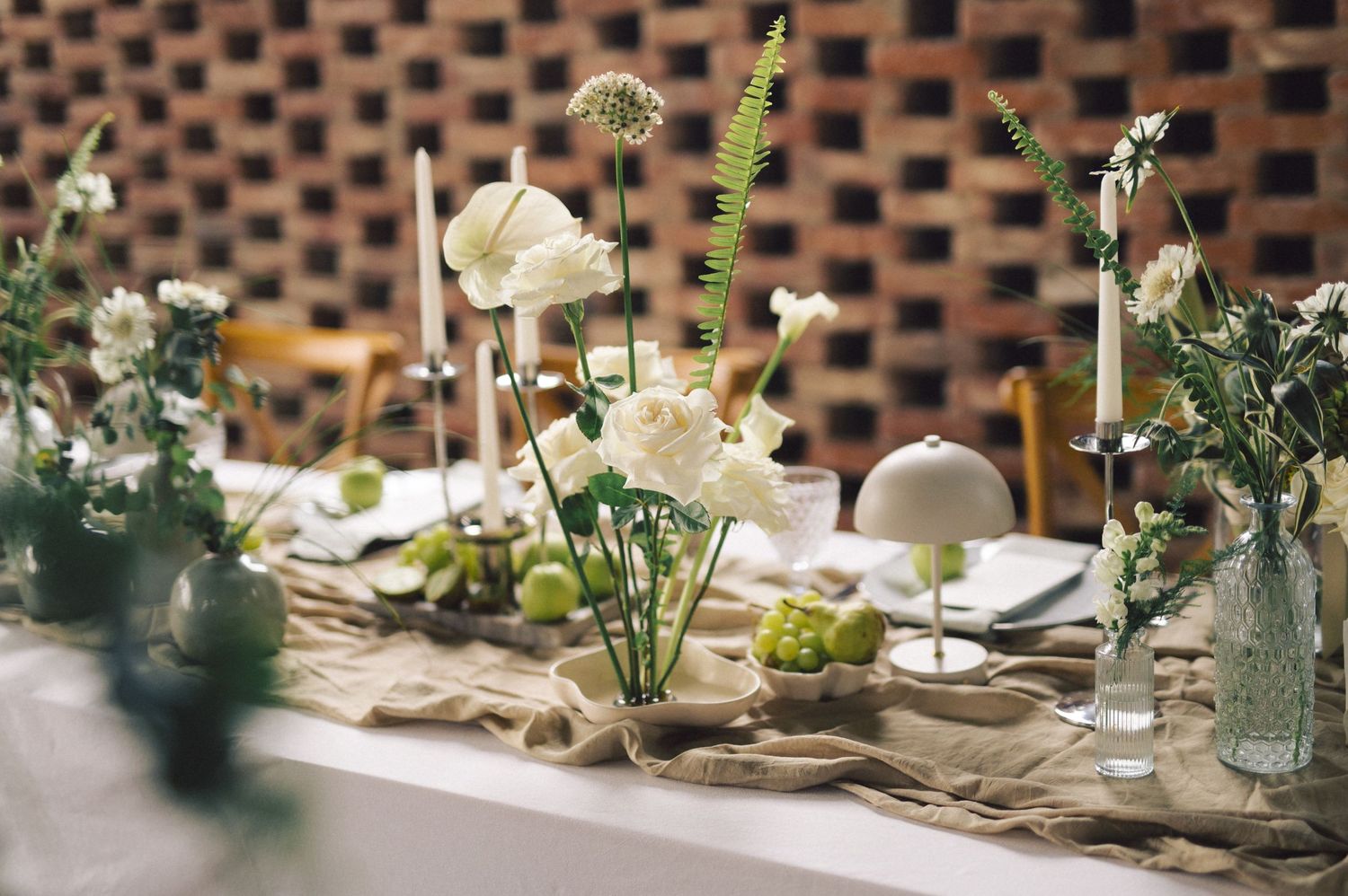 Elegant wedding centerpiece featuring white flowers and greenery on a rustic wooden table with crystal candlesticks.