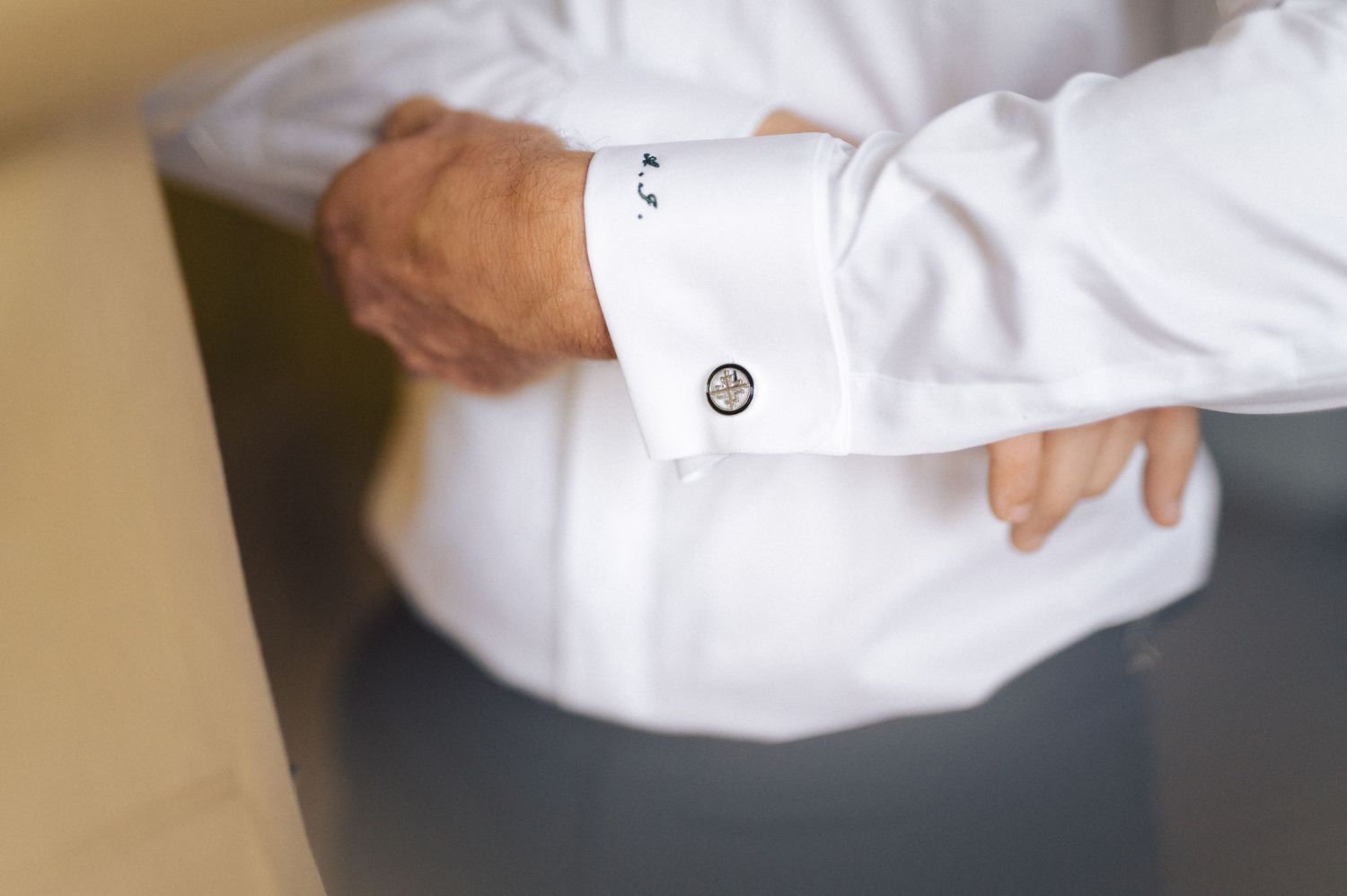 Close-up detail shot of a white dress shirt cuff with a silver cufflink.