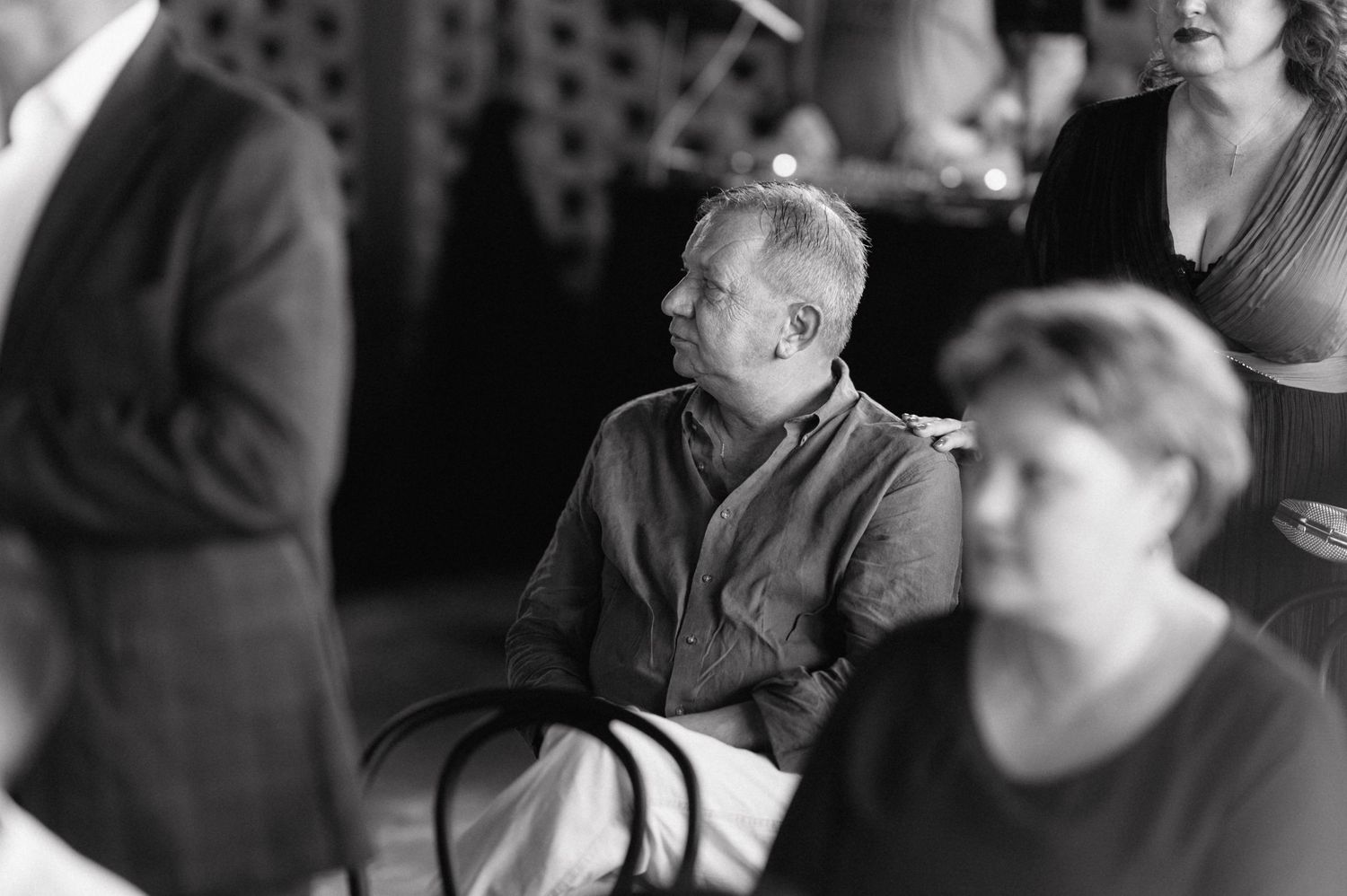 Black and white candid photograph showing people engaged in conversation at a casual indoor gathering.