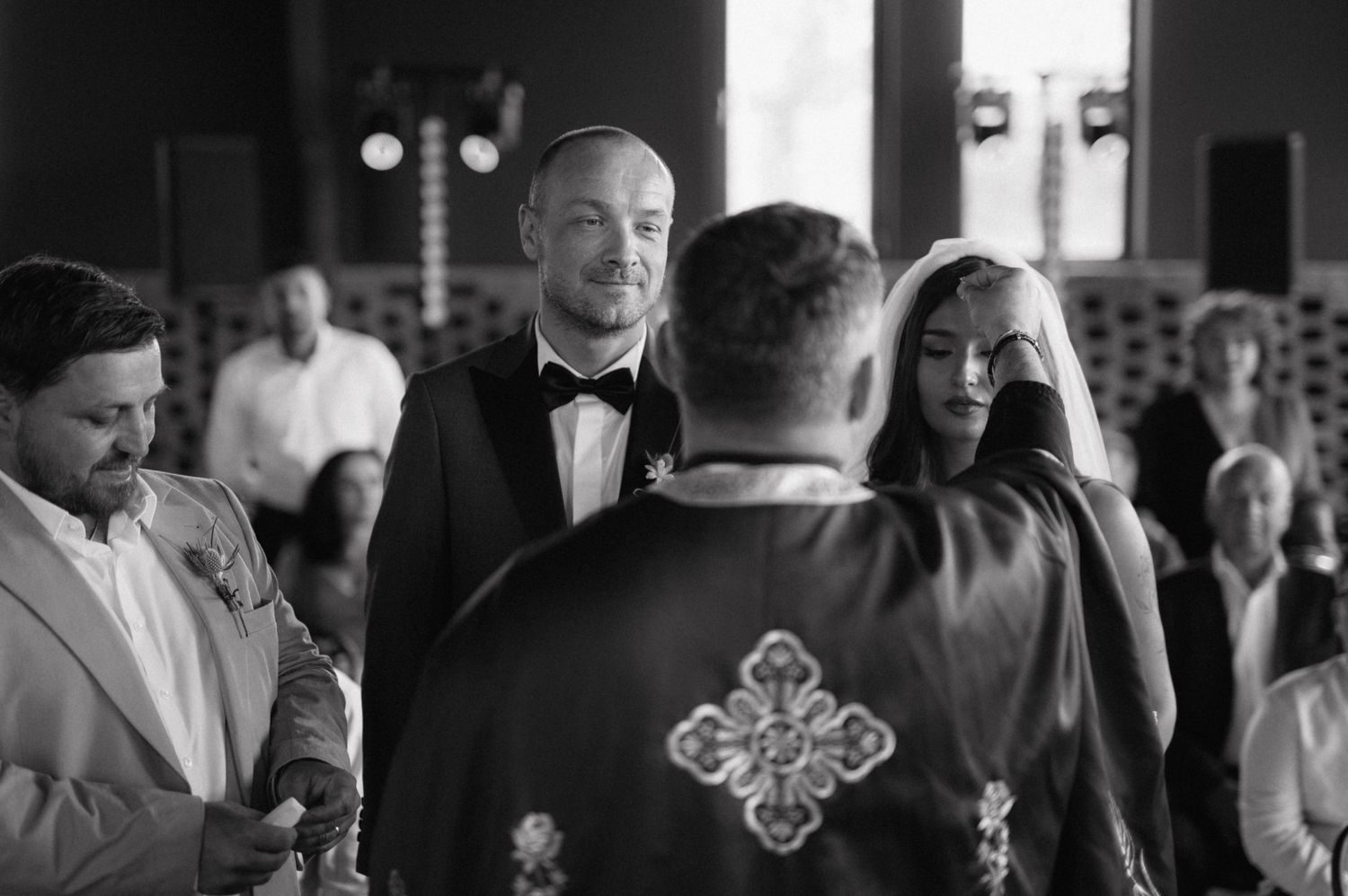 A black and white wedding party stands together in a line outdoors during a formal celebration.