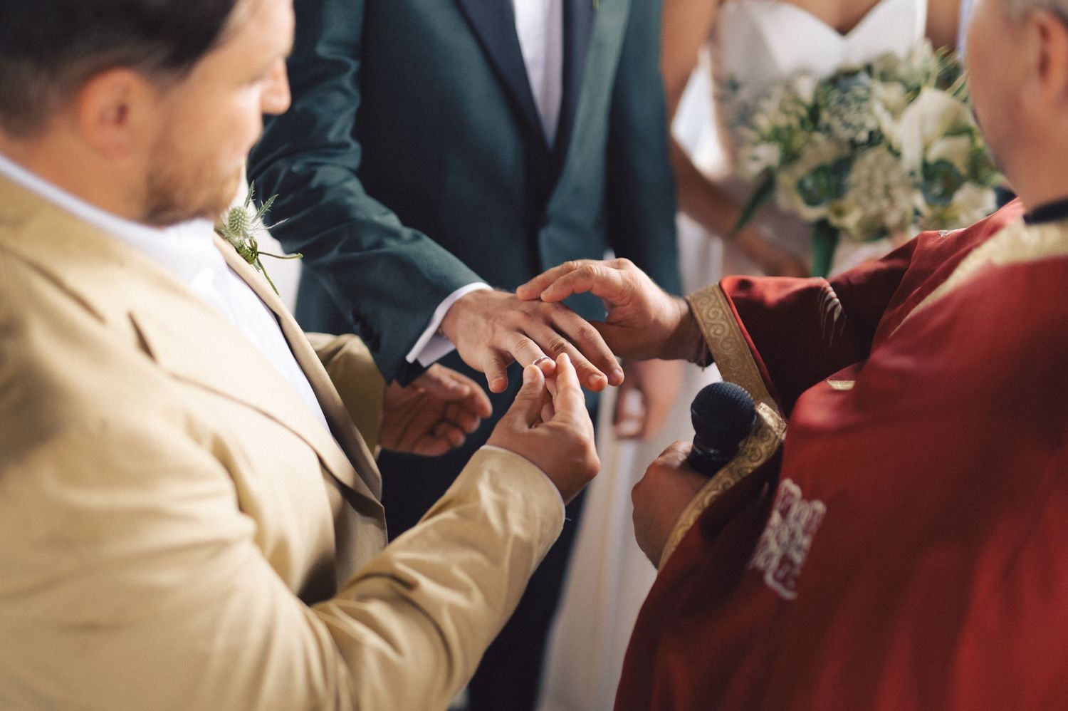 Close-up shot of hands exchanging wedding rings during a marriage ceremony.