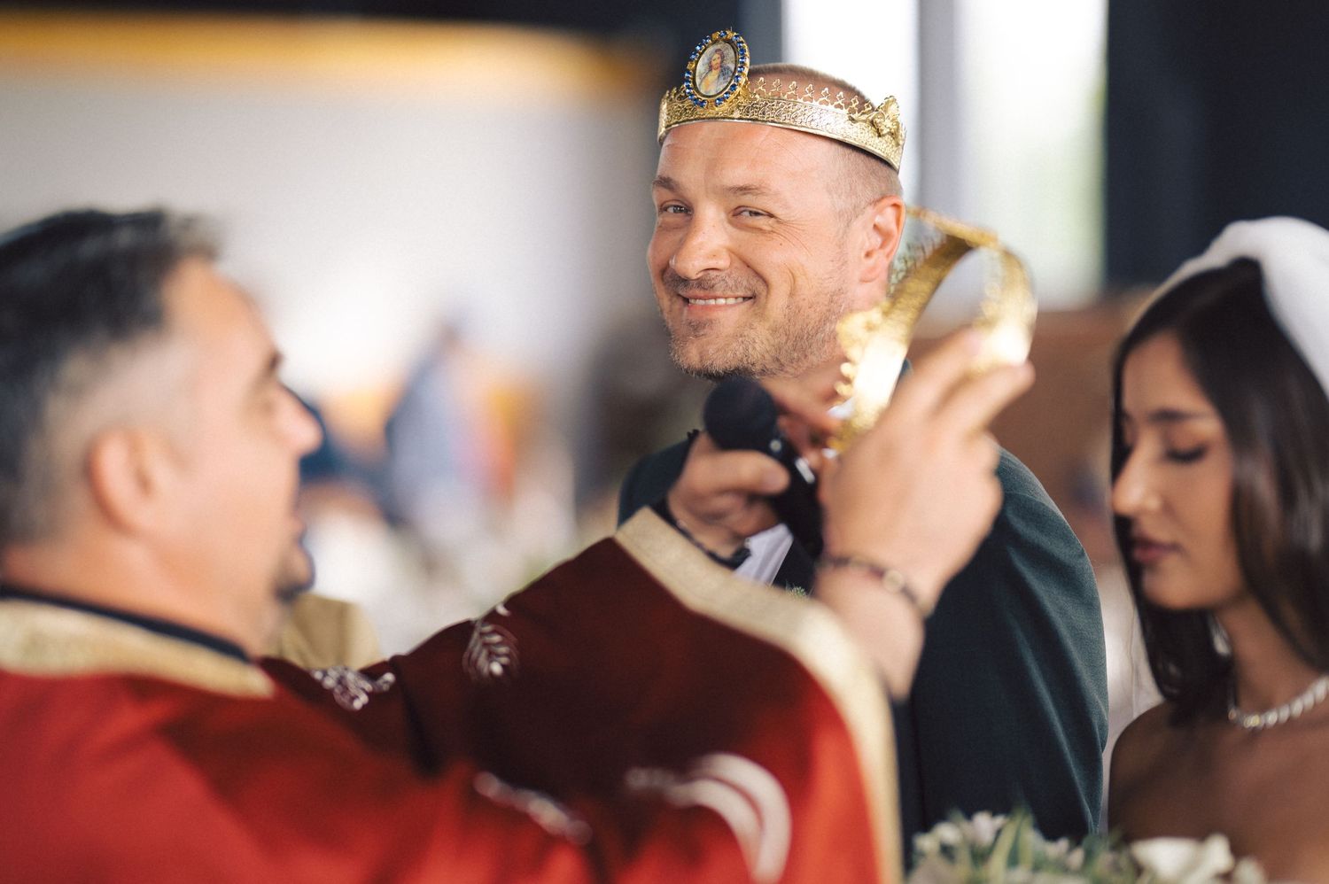 People gathered at a celebration event share laughs and drinks with one person wearing a gold paper crown.