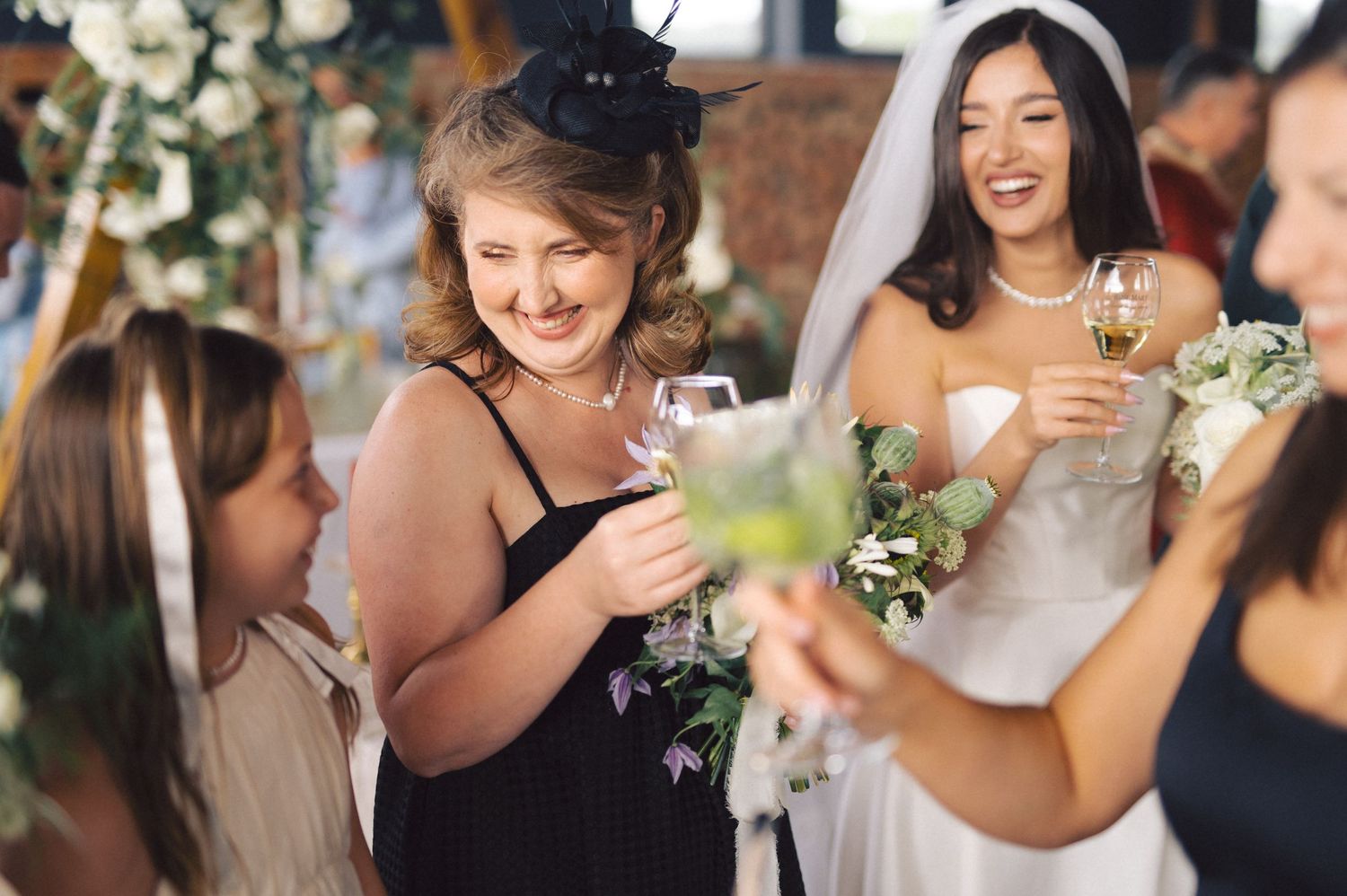 Wedding guests gather during a celebration, smiling and raising glasses in a toast at an intimate reception.