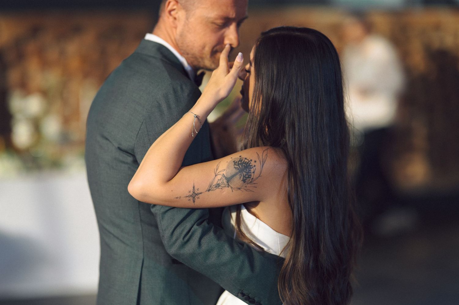 A couple shares an intimate wedding kiss outdoors during golden hour with natural light illuminating their romantic moment.