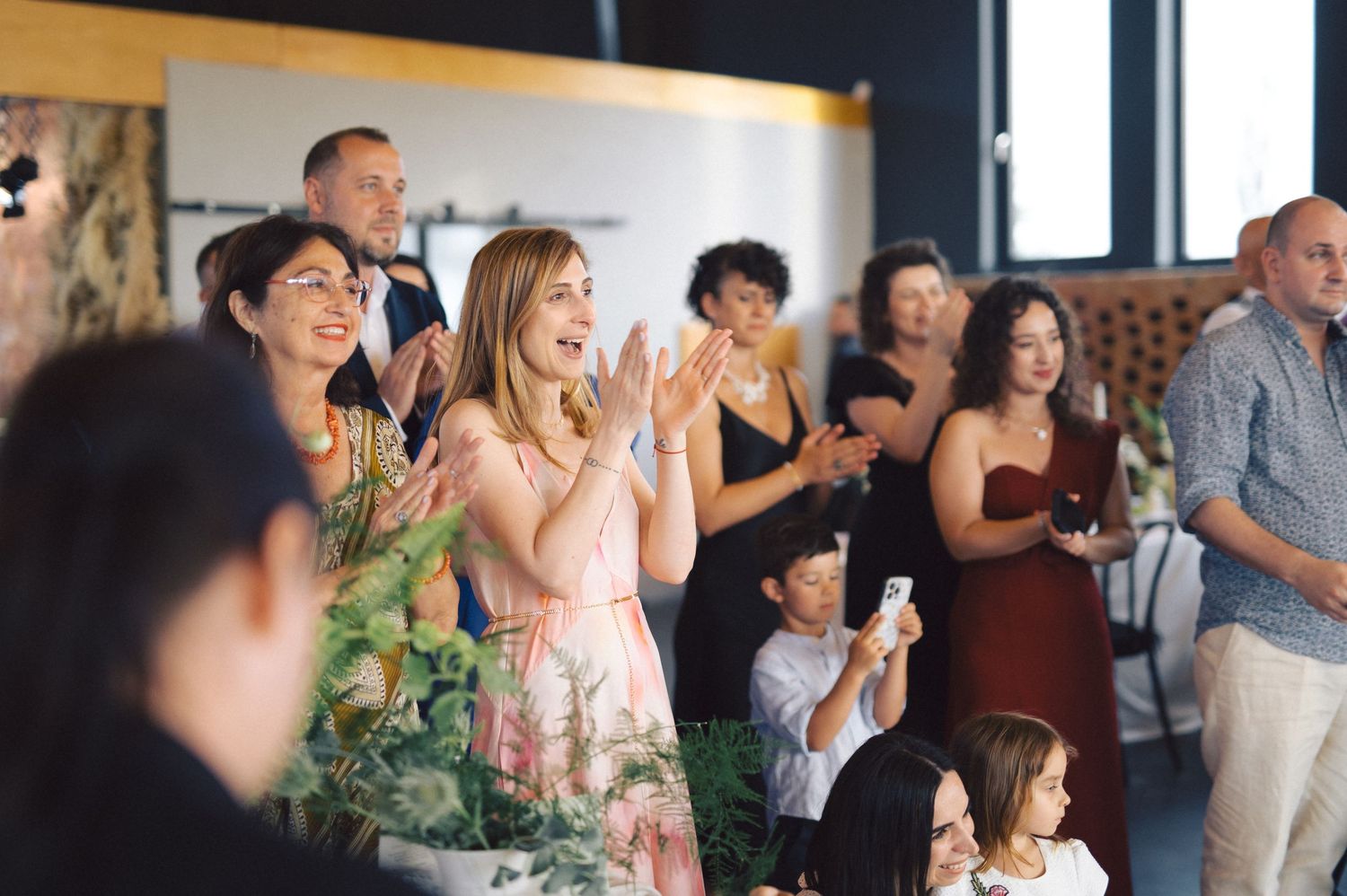 Wedding guests react with joy and excitement during a special moment at an indoor celebration.