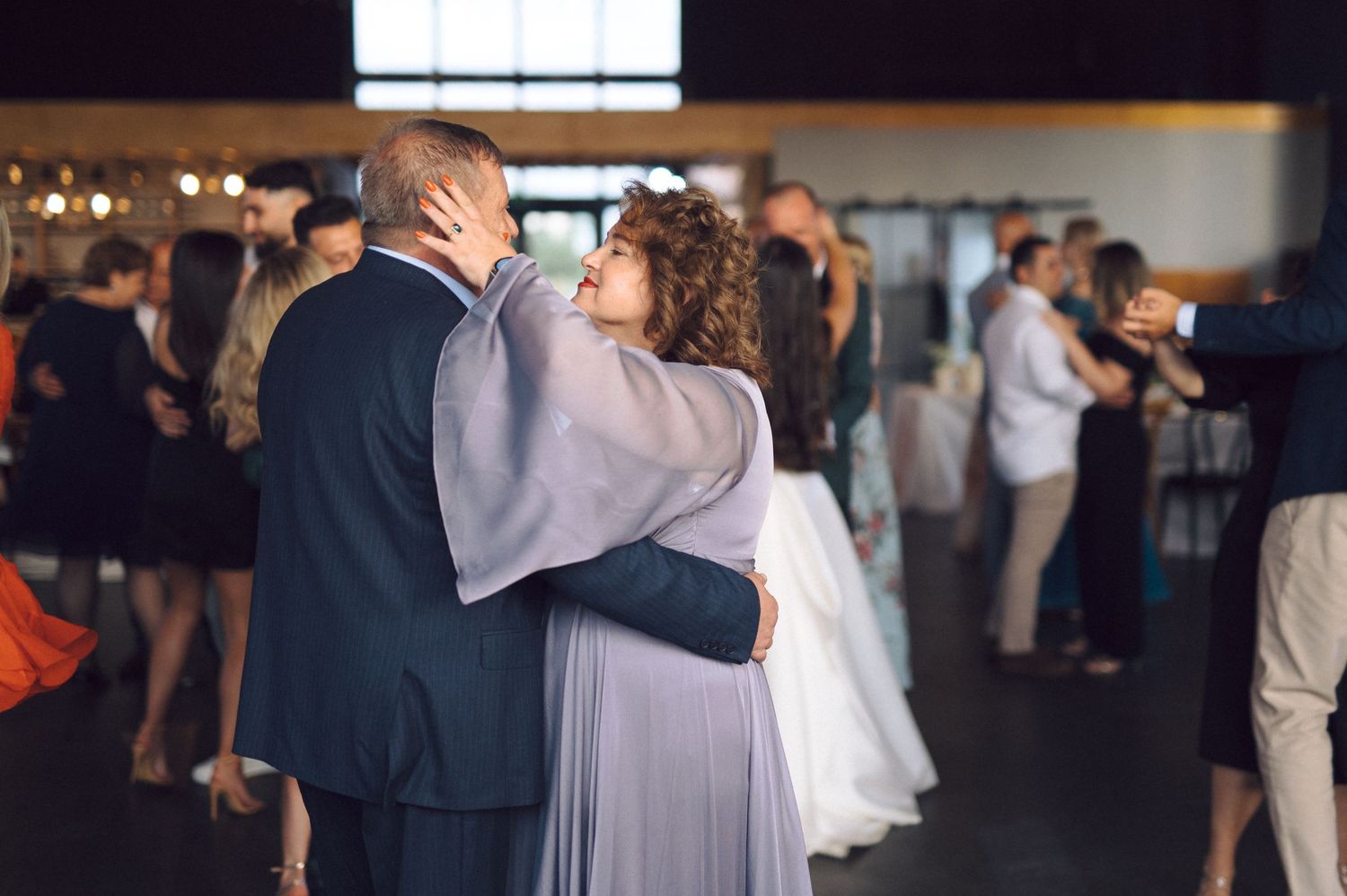 A couple dances close together in a ballroom during what appears to be their first dance at a wedding reception.