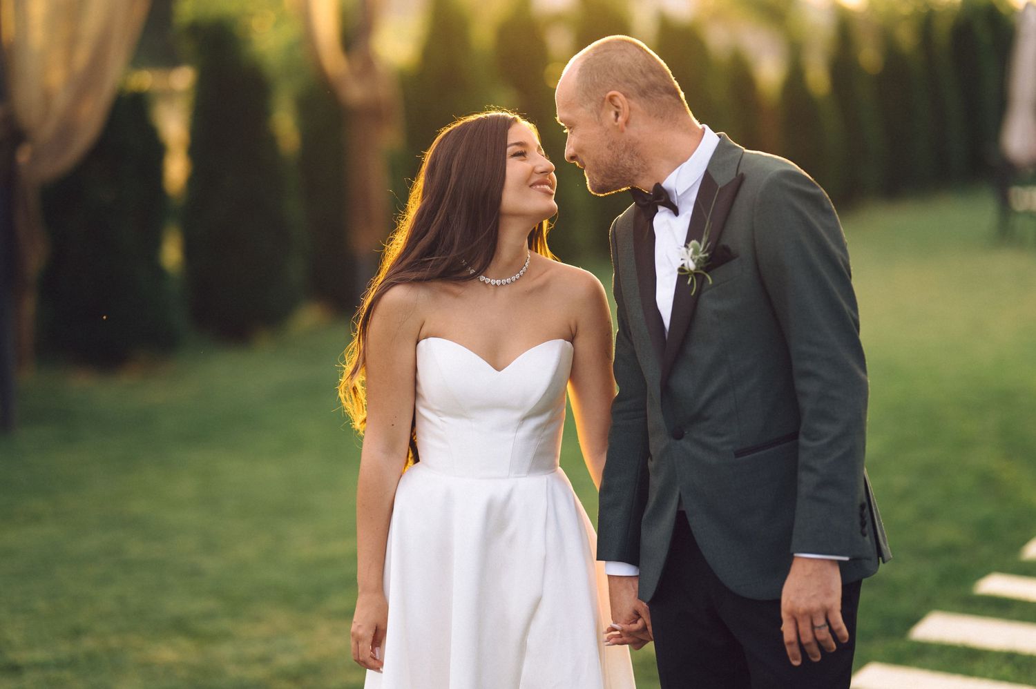 A romantic wedding photo series showing a couple in elegant attire embracing outdoors during golden hour.