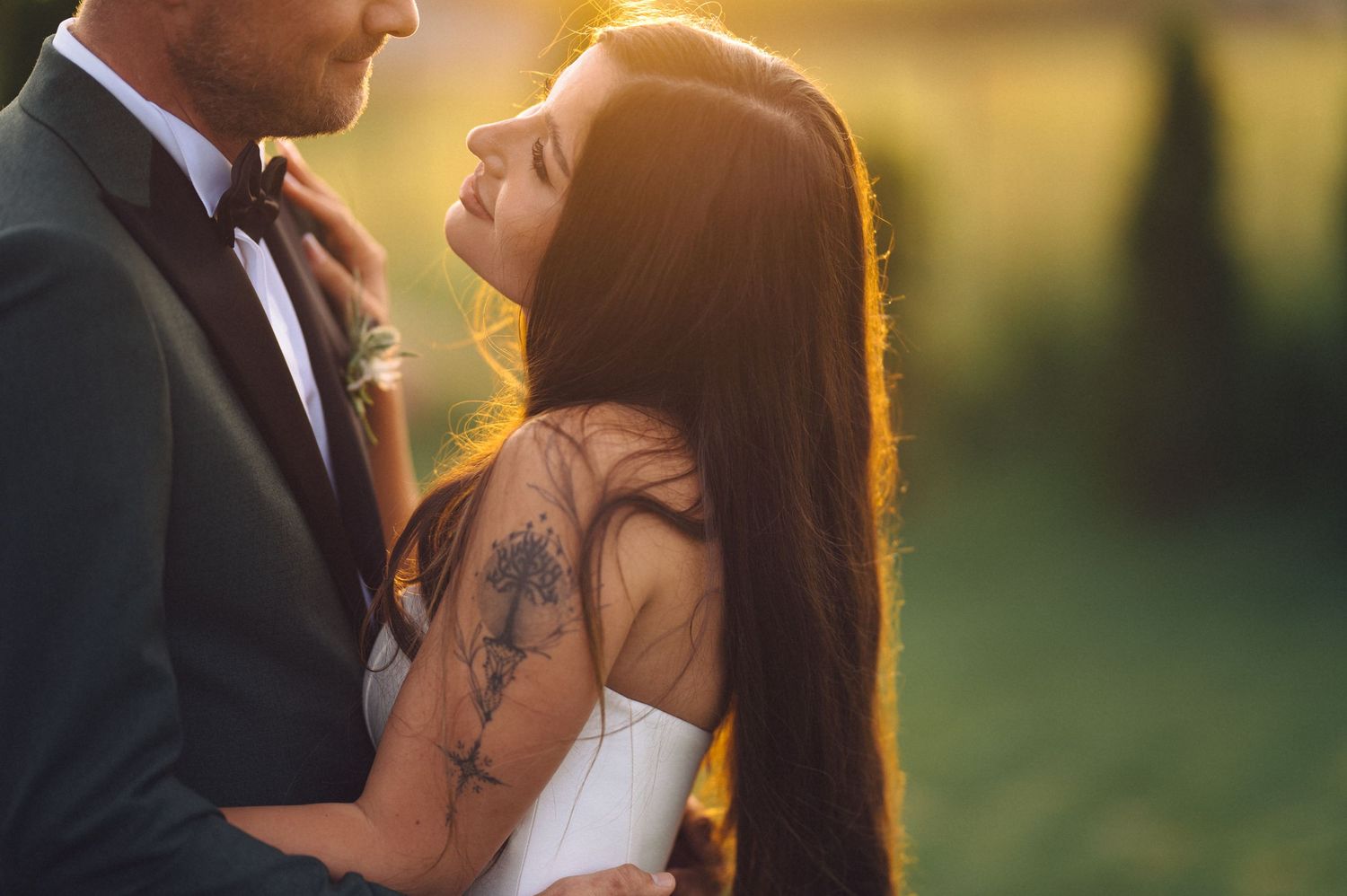 A romantic sunset wedding portrait shows a couple gazing at each other in warm golden light.