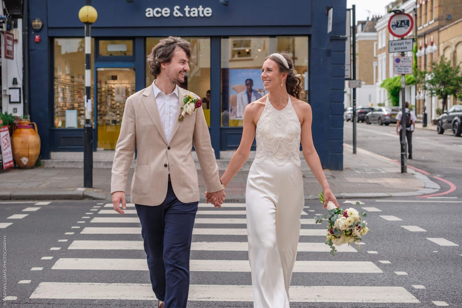 People celebrating a wedding day walk together and smile on a city street with buildings in the background.