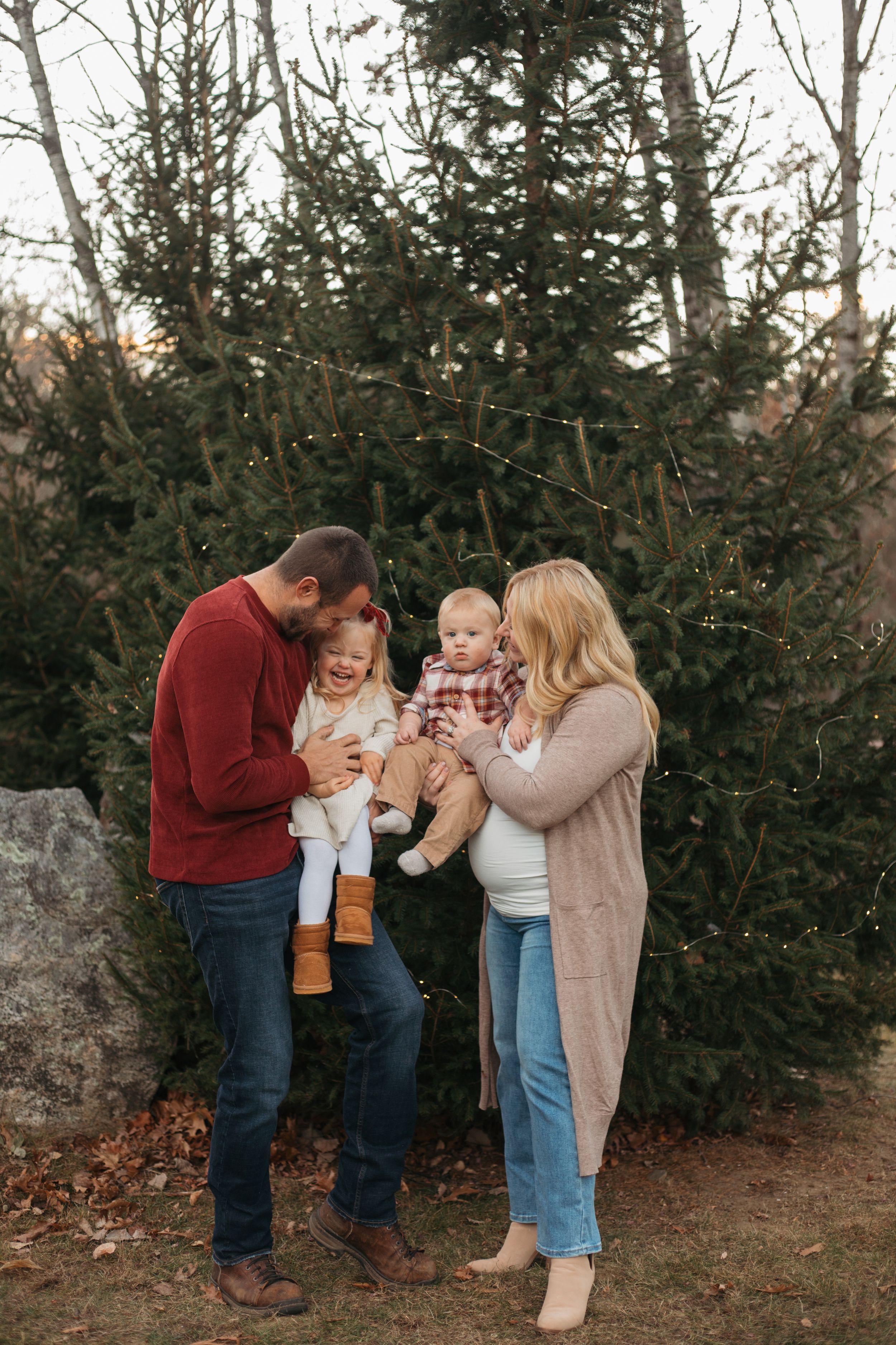 family smiling in front of a christmas tree at the park giggling together