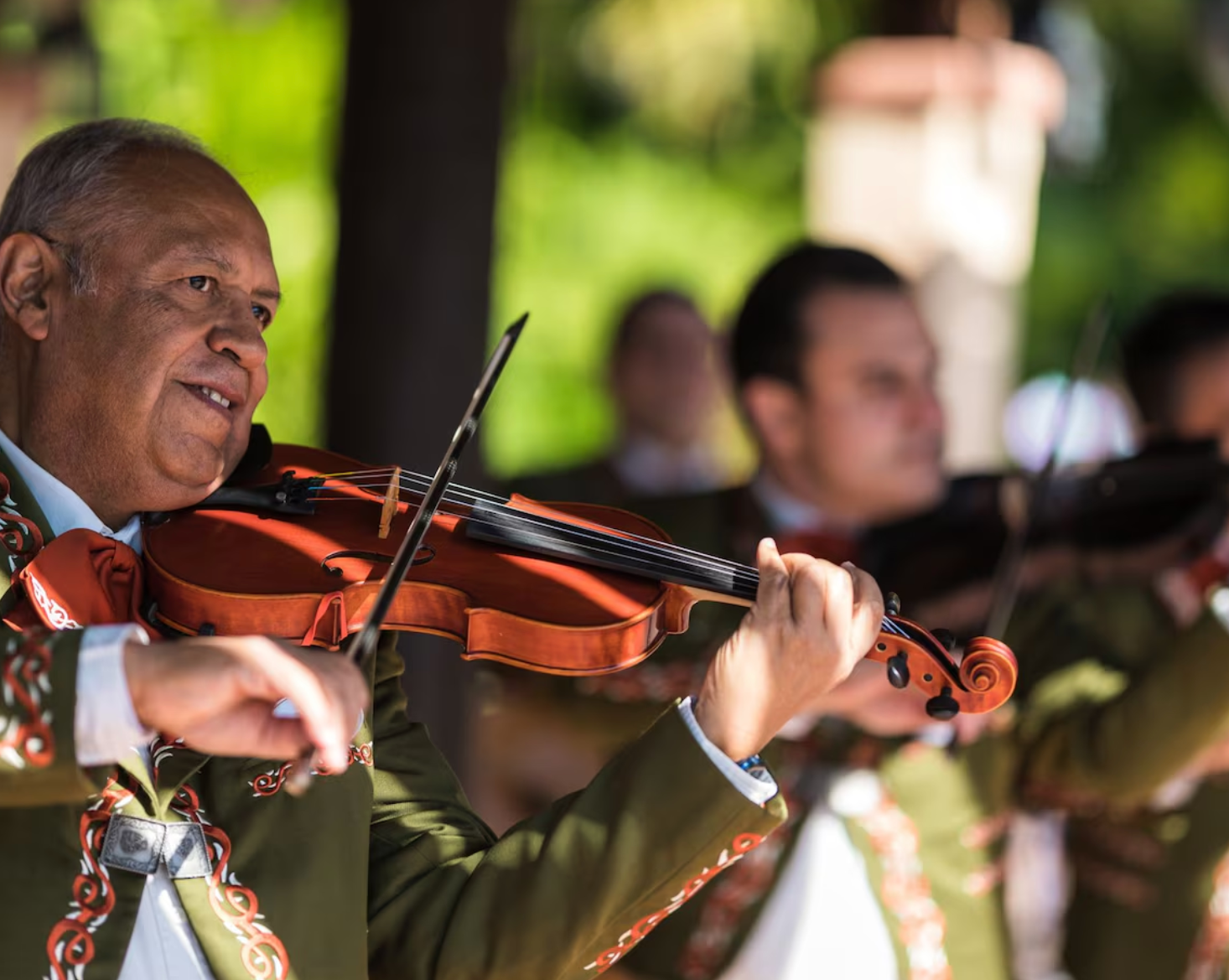 Traditional mariachi musician performing on violin during outdoor performance.