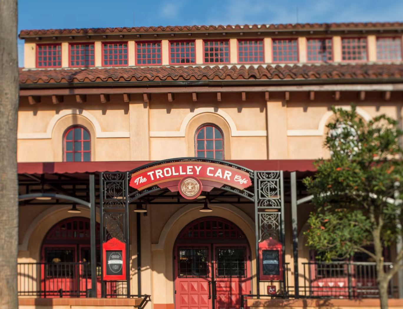 Exterior view of The Trolley Car restaurant with Spanish-style architecture and red awning.