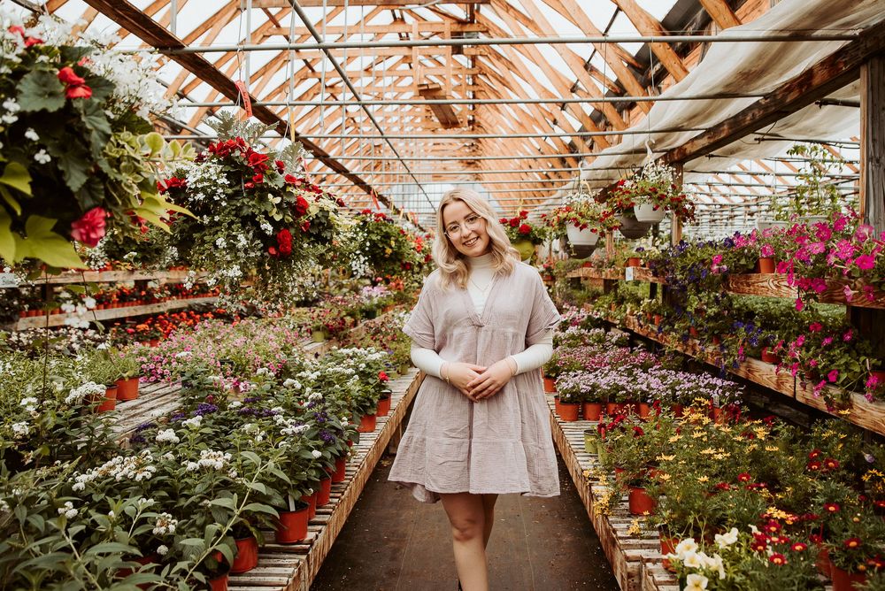 Greenhouse filled with blooming flowers and potted plants arranged along wooden benches.