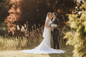 Romantic wedding couple embraces in golden sunlit field at Hall Farm - image captured by Grimsby photographers.