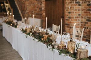 Rustic wedding reception table decorated with wooden log centerpieces and white candles at Hall Farm - captured by Grimsby photographers.