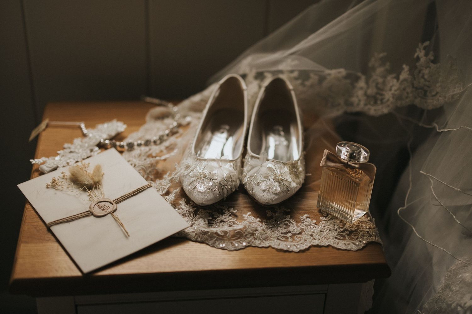 Wedding accessories and details including shoes, jewellery, and lace elements arranged elegantly on wooden surfaces.