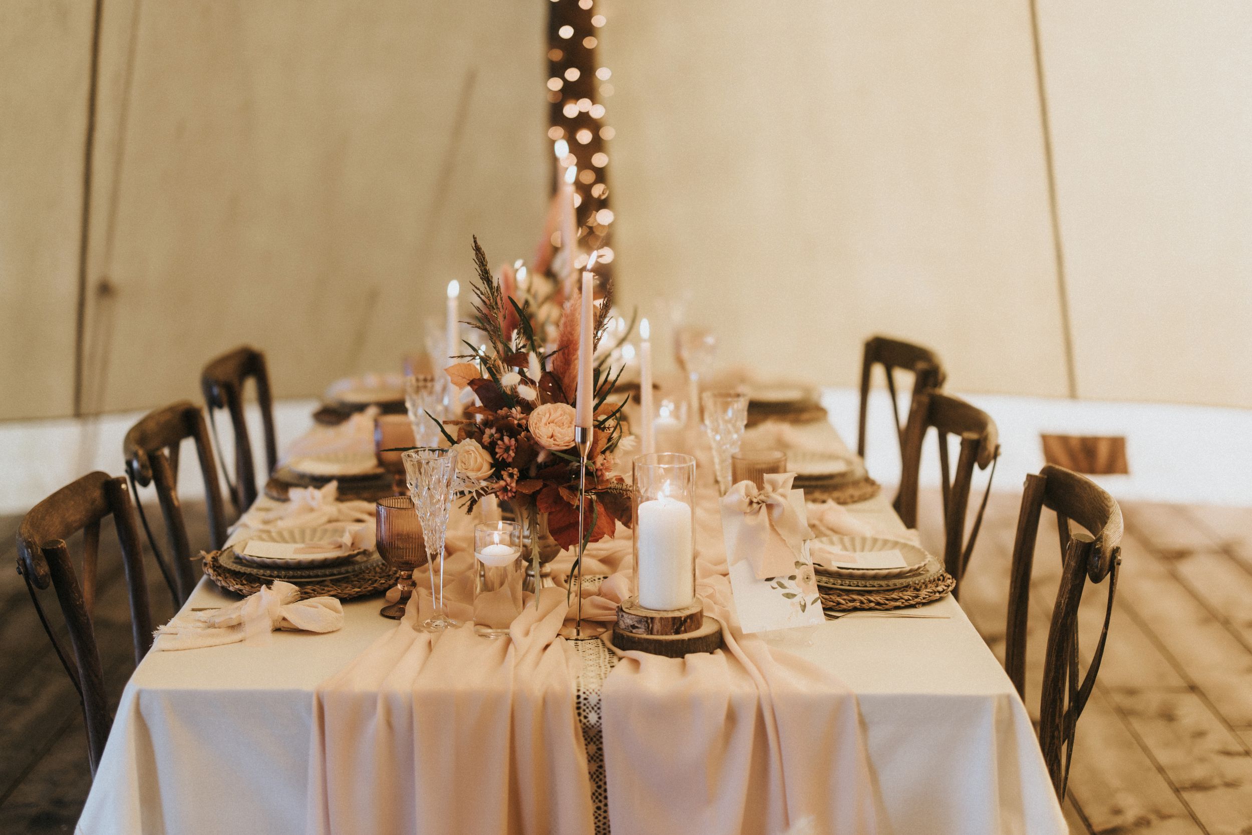 Rustic wedding reception tables set with neutral linens, dark chairs and fall floral centrepieces at Nuddock Wood Lake.