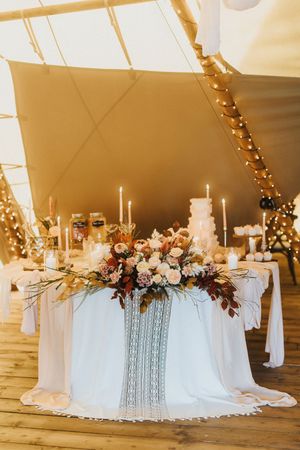 Elegant wedding reception table settings with white linens and crystal chandeliers under a sailcloth tent at Nuddock Wood Lake.