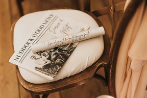 Vintage books and papers arranged on a wooden wedding chair in a warm sepia tone at Nuddock Wood Lake.