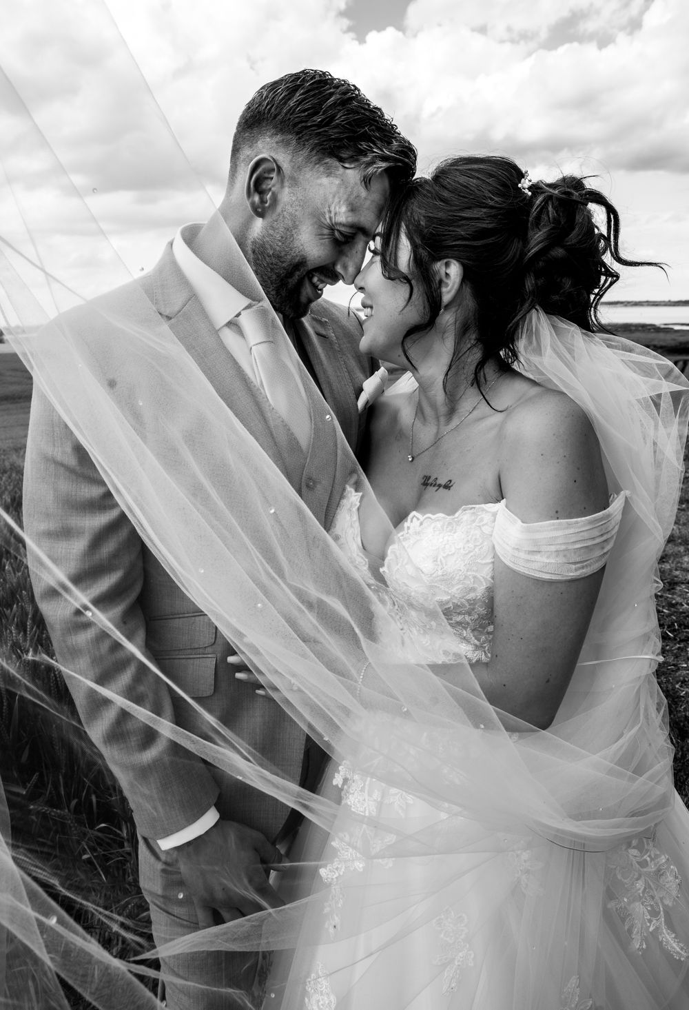 A romantic black and white portrait of newlyweds sharing an intimate moment with flowing veil.