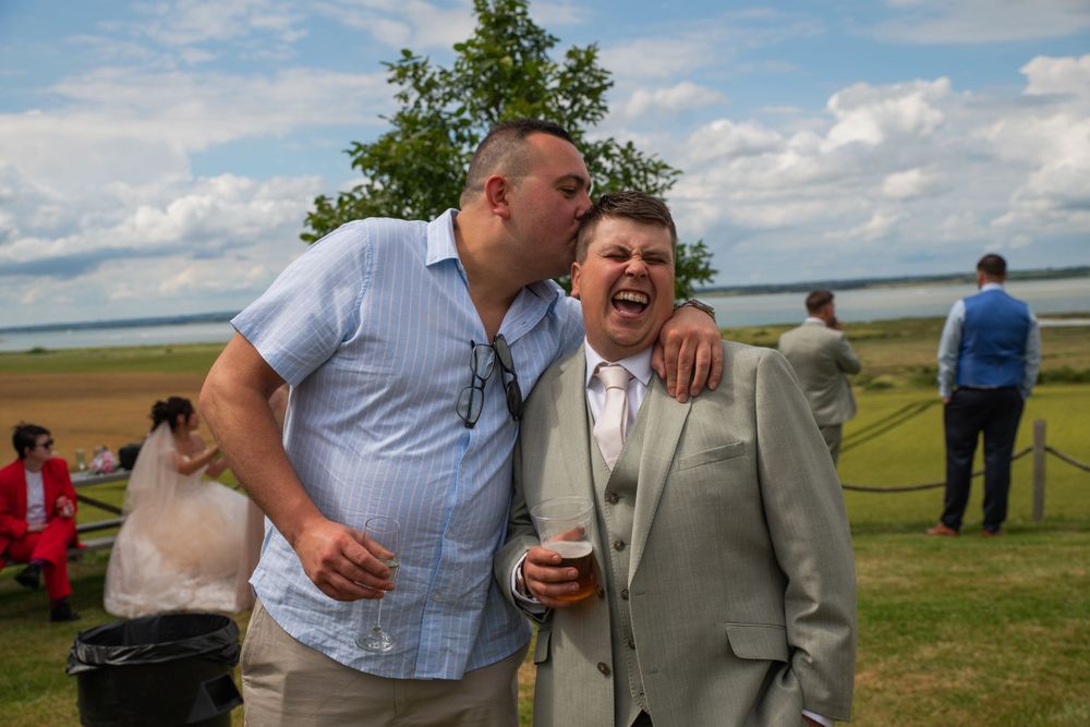 A joyful moment shared between wedding guests on a sunny day outdoors.