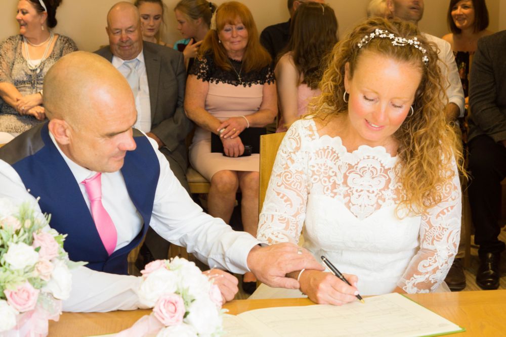 A couple signs their wedding registry during an indoor ceremony.