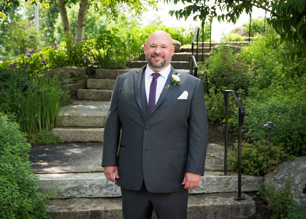 Four images of a suited figure standing near stone steps and landscaping in an outdoor garden setting.