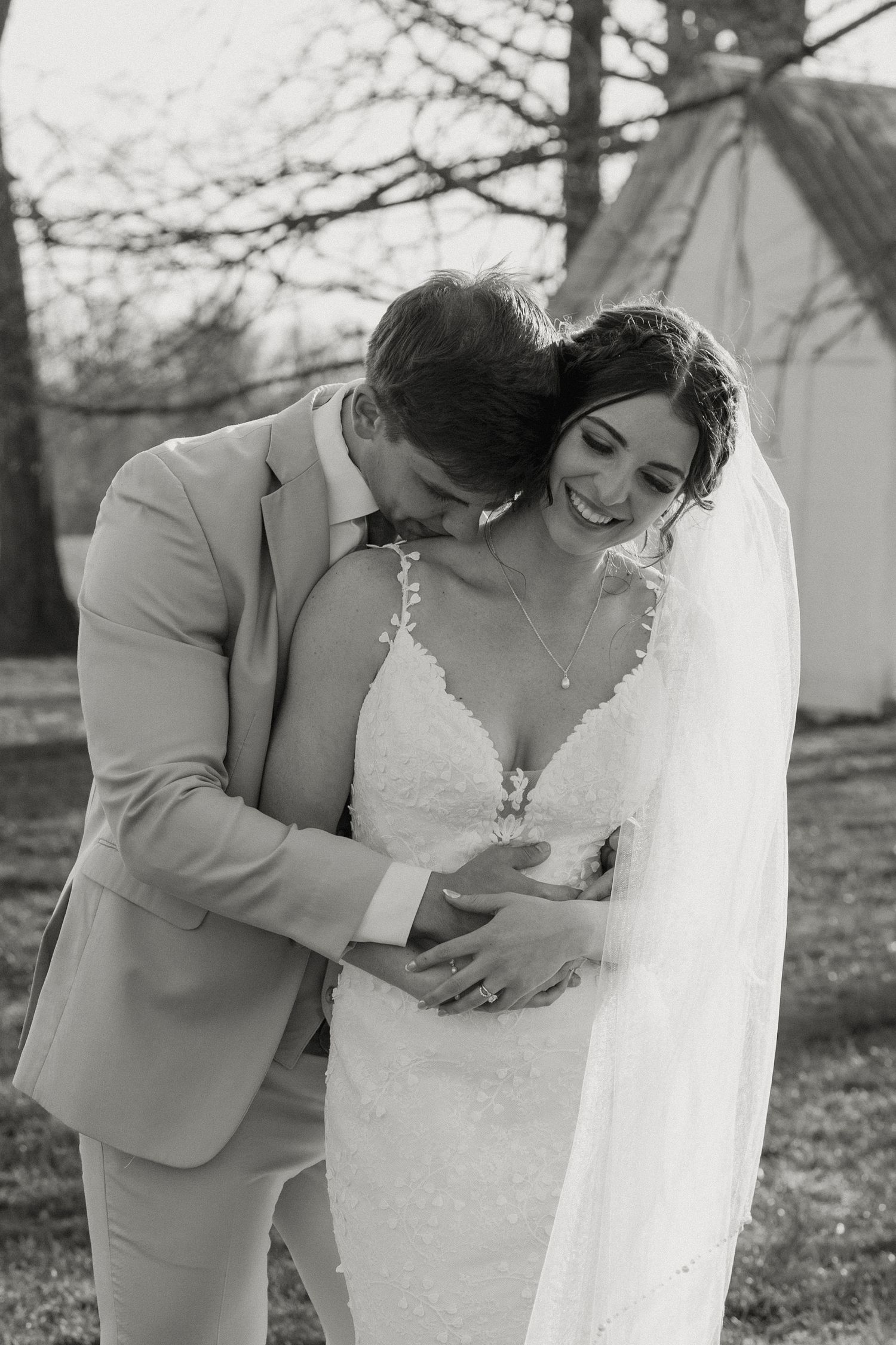 Close-up photo of hands gently holding white veil against a wedding dress with the engagement ring in focus.