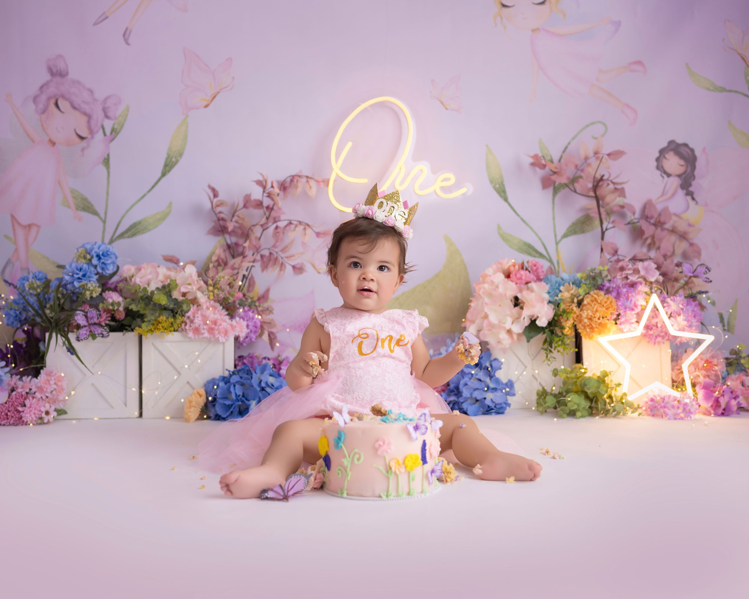 Birthday photo setup with fresh flowers, neon signage, and pink and blue color scheme.