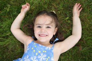 A series of connected photos showing someone in a blue floral dress lying in green grass with arms raised.