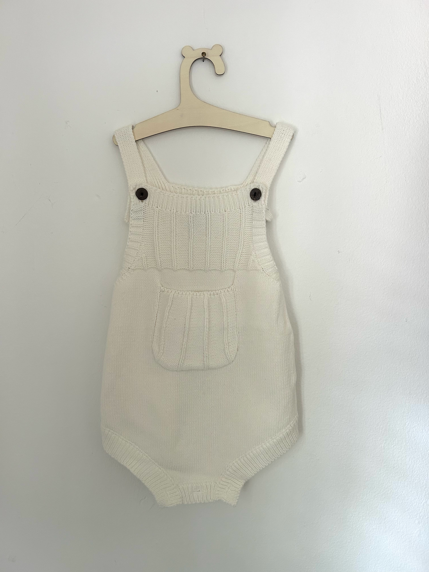 White baby romper with delicate pink embroidered floral design and ruffle details on straps.
