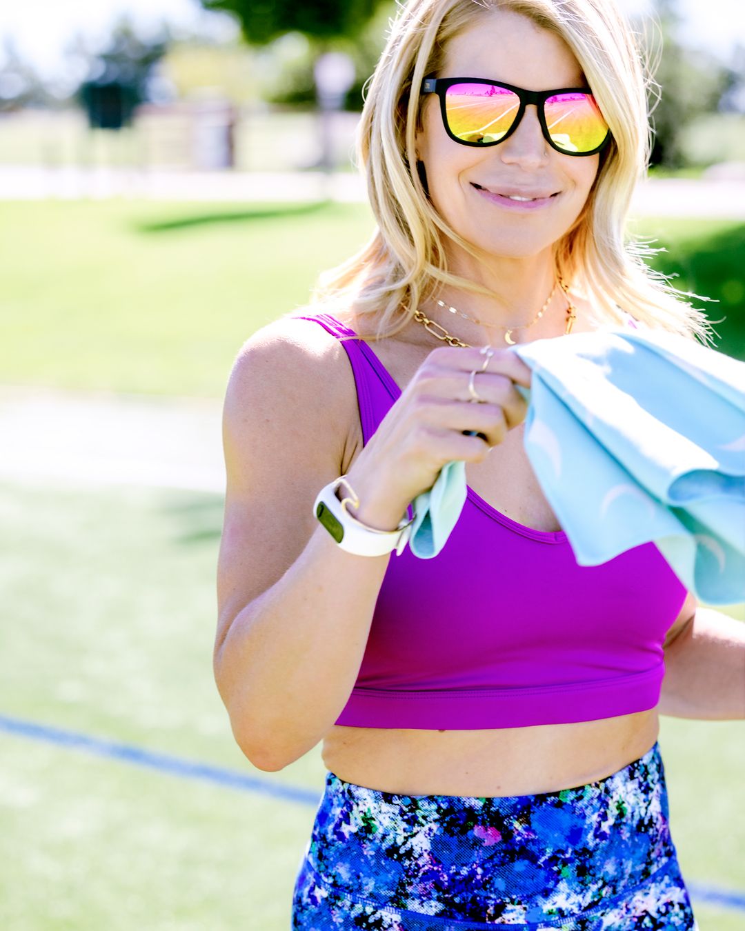 Person in purple crop top and patterned shorts wearing reflective sunglasses outdoors on sunny day while shopping.