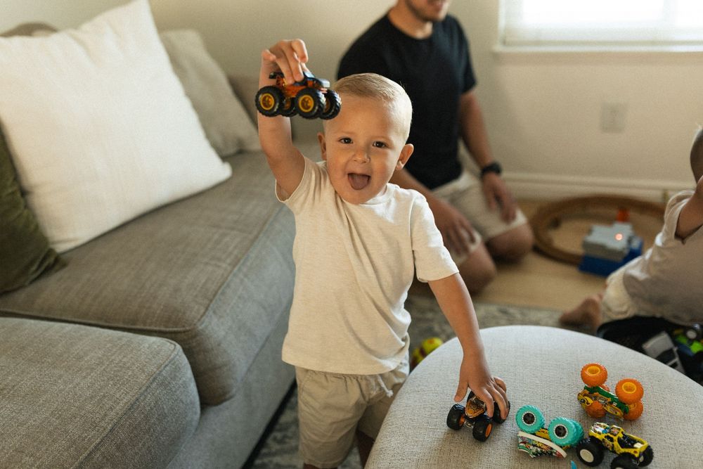 Playtime in living room with toys scattered on grey couch and coffee table.