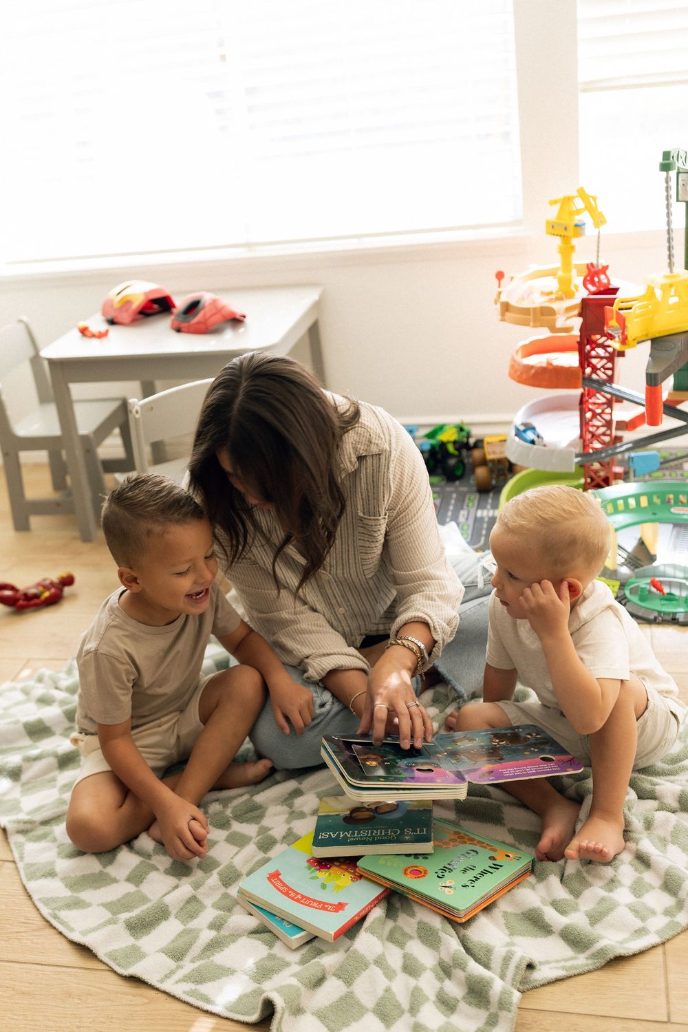 Intimate storytime on a gray and white patterned rug with children's books spread around.