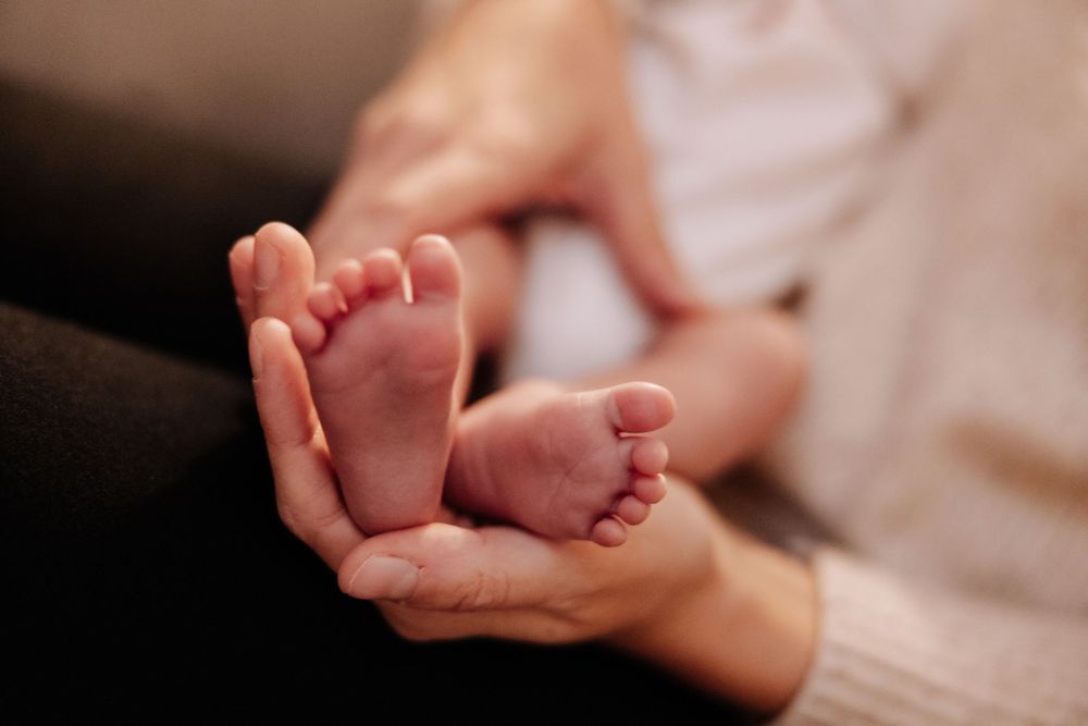 Tiny newborn baby feet resting gently in caring adult hands.